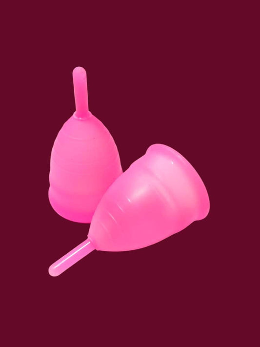 Bright pink reusable menstrual cup with easy-grip stem on dark background